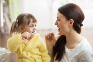 A woman brushing her teeth with a child