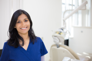 A smiling dental assitant by a dental chair